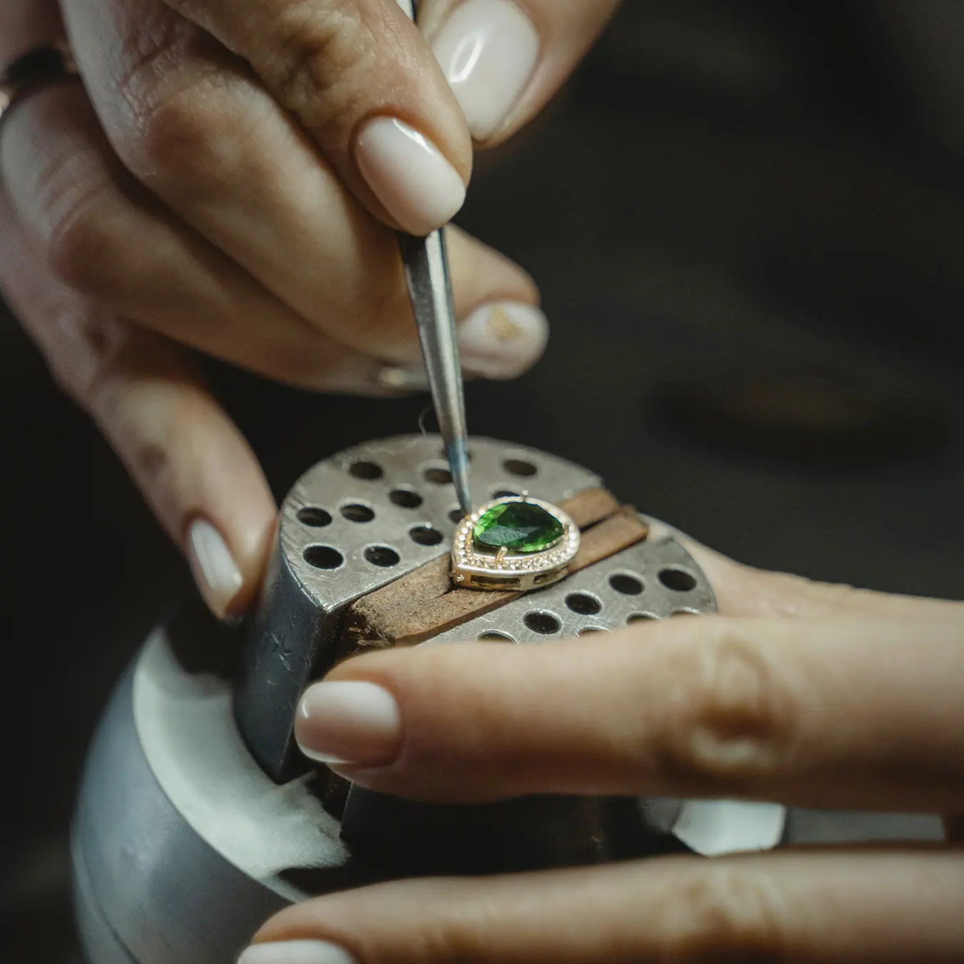 An artisan setting a green gemstone at the bench