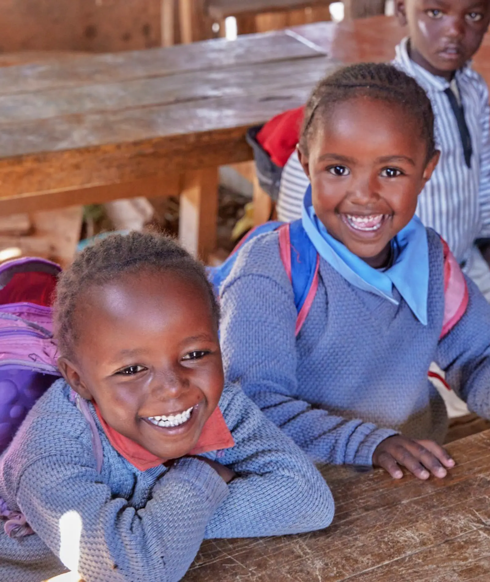 Two smiling schoolchildren resting on a wooden classroom desk