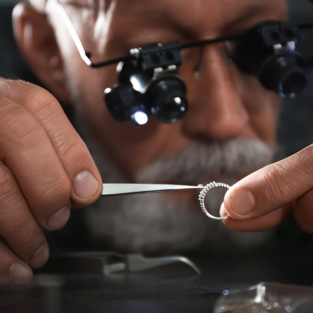 Male jeweller evaluating diamond ring in workshop, closeup view